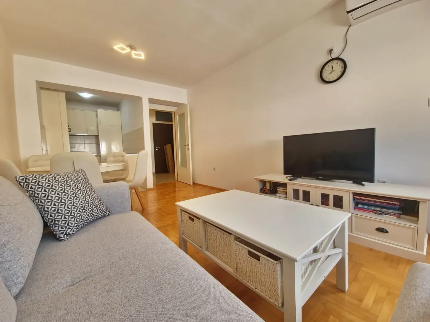 Living room with a sofa, coffee table and television, with a view of the dining area and kitchen.