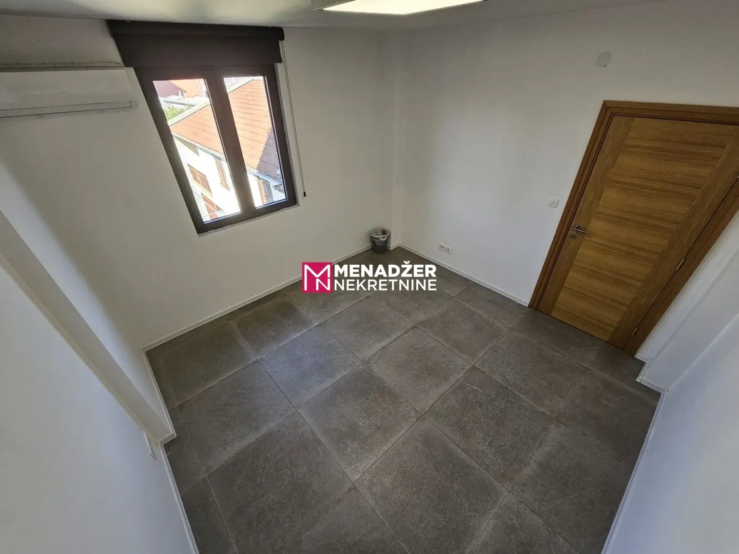 Empty room with tiled flooring and a wooden door.