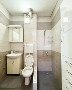 Manje kupatilo obloženo keramičkim pločicama sa tuš kabinom, lavaboom i toaletom. - image 11