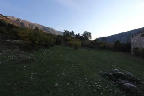 Zeleni plac na blagoj padini okružen planinskim pejzažem. - image 5