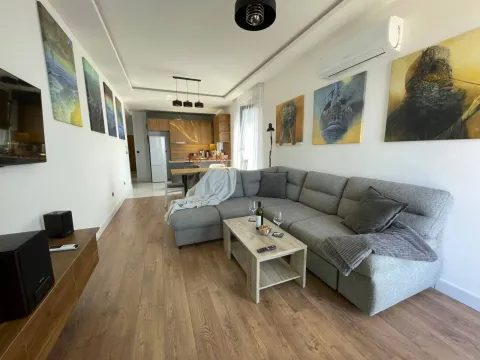 Living room with a sectional sofa, coffee table, and kitchen in the background. - image 25