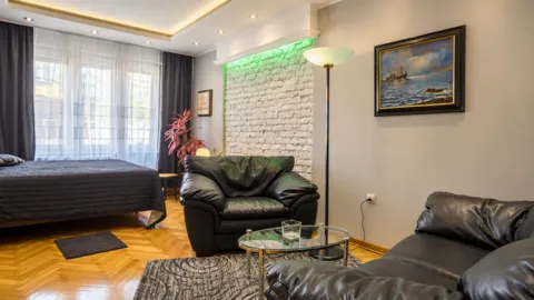 Living room with black leather sofas, a coffee table, and a decorative brick wall. - image 6
