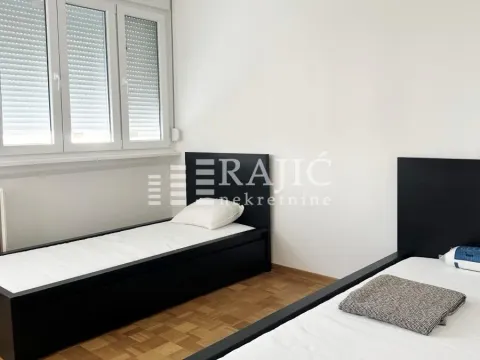 Furnished bedroom with two single beds and white walls. - image 7