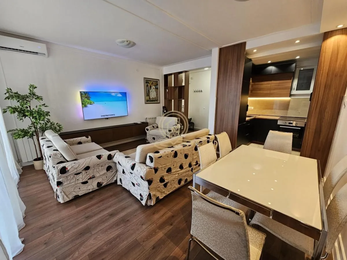 Living room with a sofa, TV, and an adjoining dining area.
