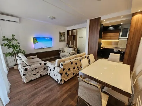 Living room with a sofa, TV, and an adjoining dining area. - image 8