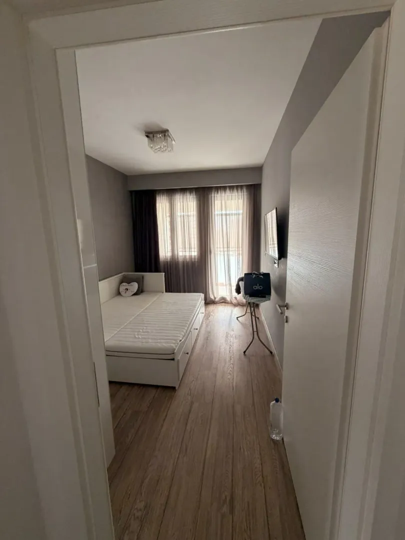 Pogled iz hodnika na namještenu spavaću sobu sa krevetom i prozorom.