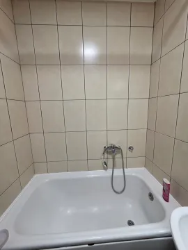 Small bathroom with a bathtub and beige wall tiles. - image 13