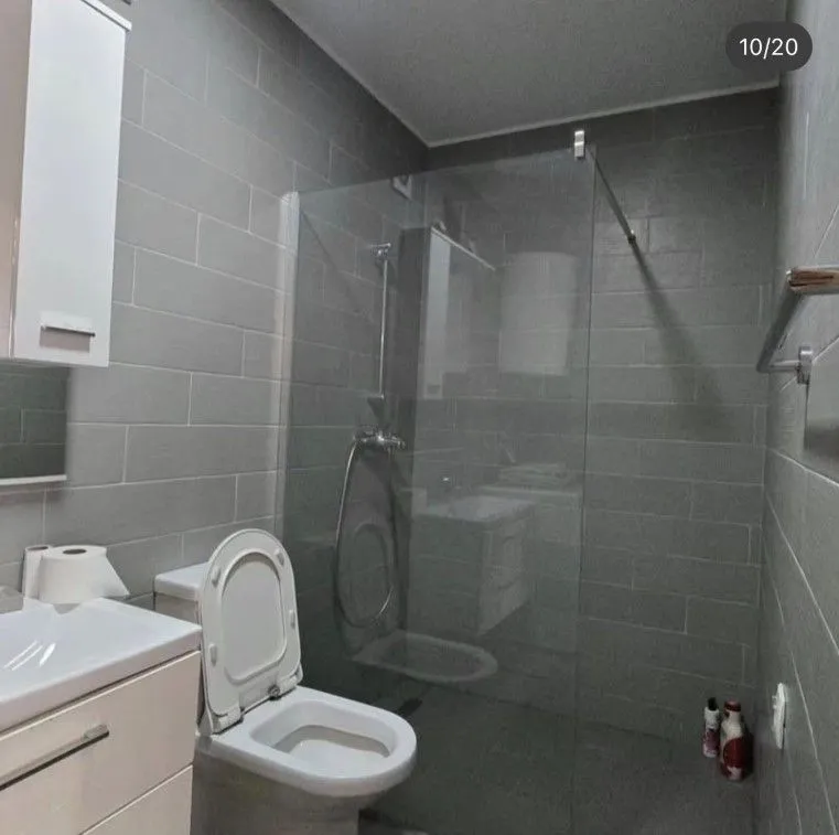 Modernly equipped bathroom with a walk-in shower and grey ceramic tiles.
