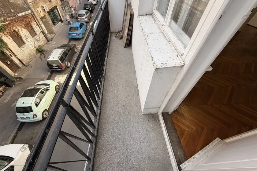 A narrow balcony with a metal railing and a street view.