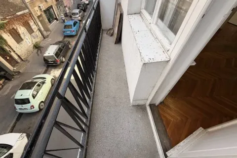 A narrow balcony with a metal railing and a street view. - image 14