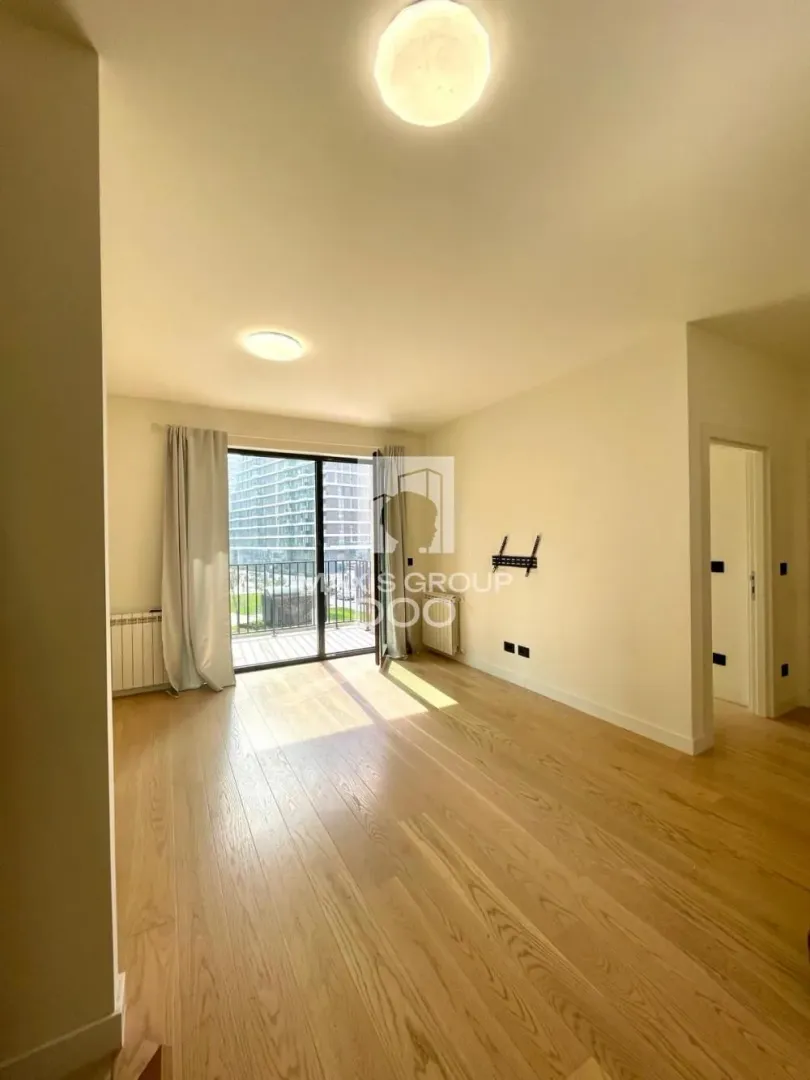 Empty living room with wooden flooring and access to the terrace.