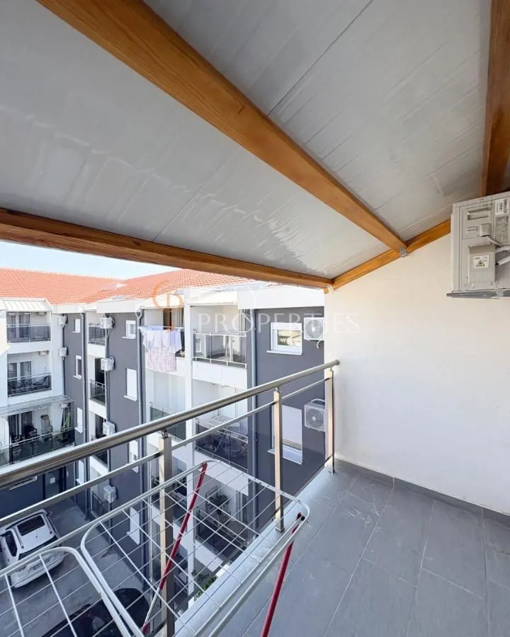 Covered balcony space with metal railing and a view of the building.