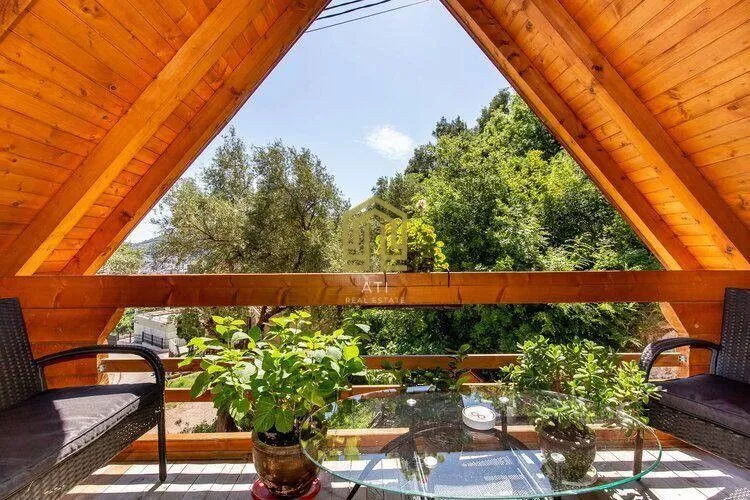 Wooden terrace with seating furniture and a view of greenery.