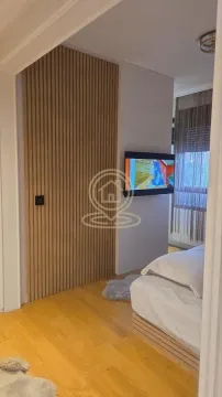 Spavaća soba sa bračnim krevetom, drvenim zidnim panelom i televizorom. - image 9