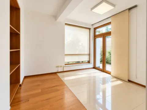 Empty bright room with wooden flooring, built-in shelving, and glass doors leading to the terrace. - image 15