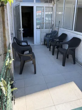 Zastakljena terasa sa crnim plastičnim stolicama i izlazom u enterijer. - image 7