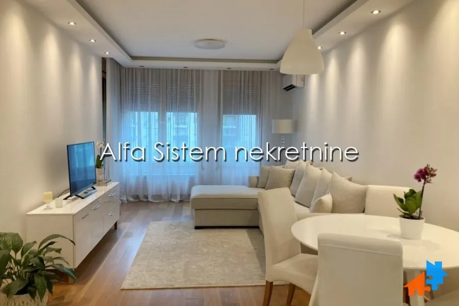 Living room with sofa, TV unit and dining table.