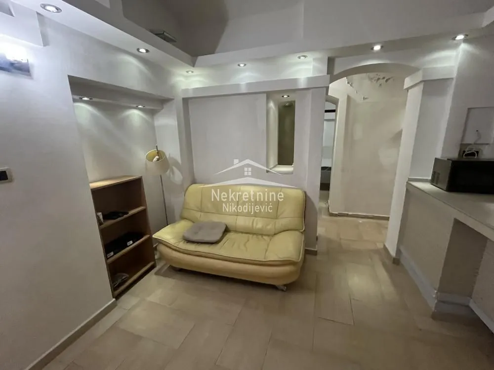 Living room with a beige sofa and a shelving unit.