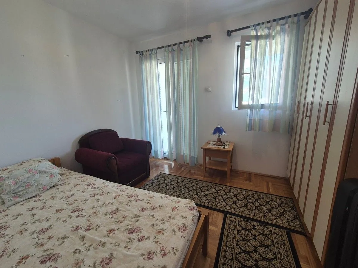 Furnished bedroom with a bed, armchair, and wardrobe.
