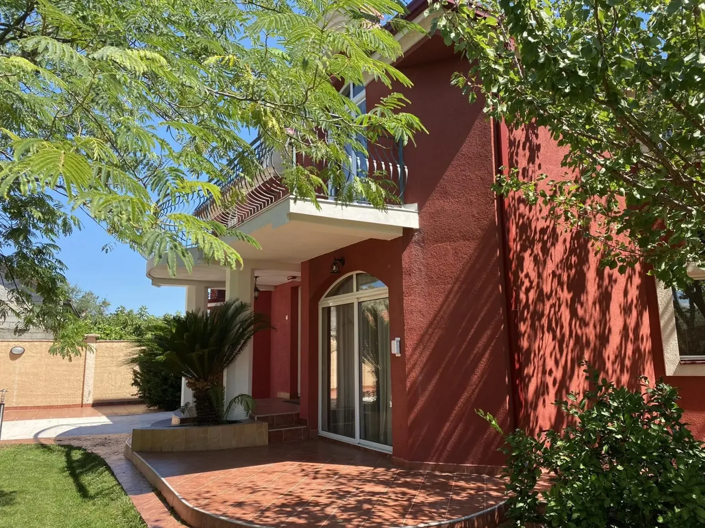Exterior of a house with a red facade and a landscaped yard.