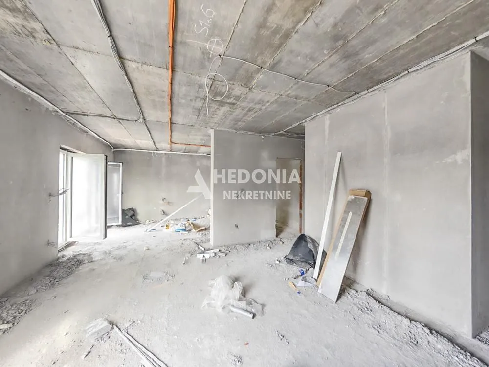 Neuređen prostor u grubim radovima sa betonskim plafonom i neokrečenim zidovima.