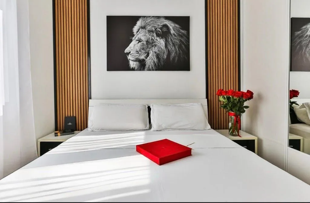 Furnished bedroom with a double bed, decorative wall panels and an art painting.