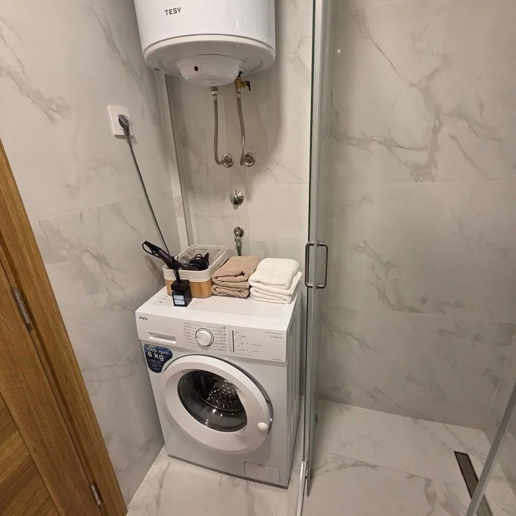 Bathroom with a washing machine, boiler, and shower cabin.