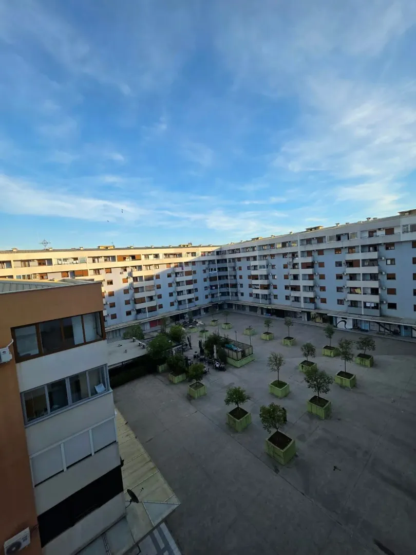 Pogled na dvorište i fasadu stambene zgrade.