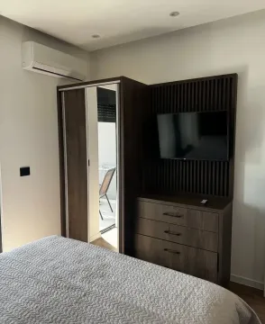 Furnished bedroom with a double bed, wardrobe, and TV. - image 7