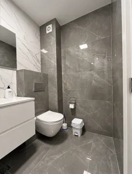 Moderne kupatilo obloženo sivim pločicama sa ugradnim toaletom i umivaonikom. - image 7
