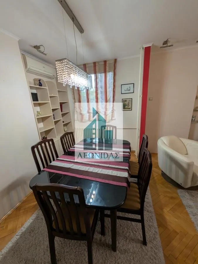 Trpezarija sa stolom, stolicama i policama u dnevnoj sobi.