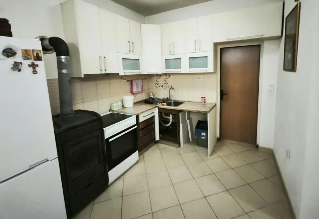 Kitchen with white cabinetry, wood-burning stove, and refrigerator.