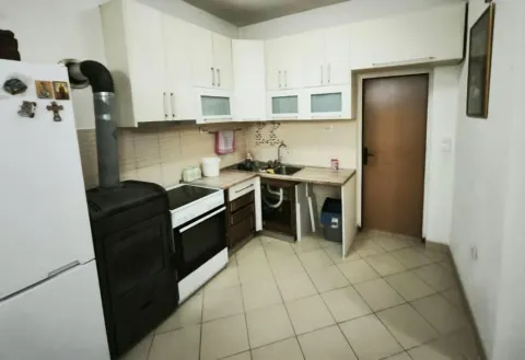 Kitchen with white cabinetry, wood-burning stove, and refrigerator. - image 4