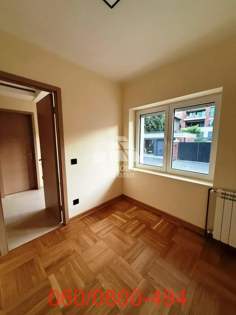 Prazna soba sa parketom i prozorom.