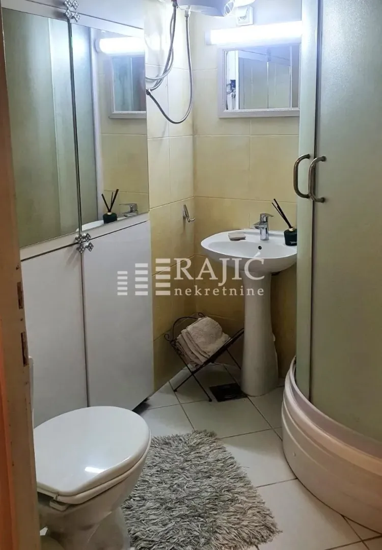 Smaller bathroom with a sink, toilet, and shower cabin.