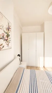 Bright bedroom with a white bed, wardrobe, and a painting on the wall. - image 6