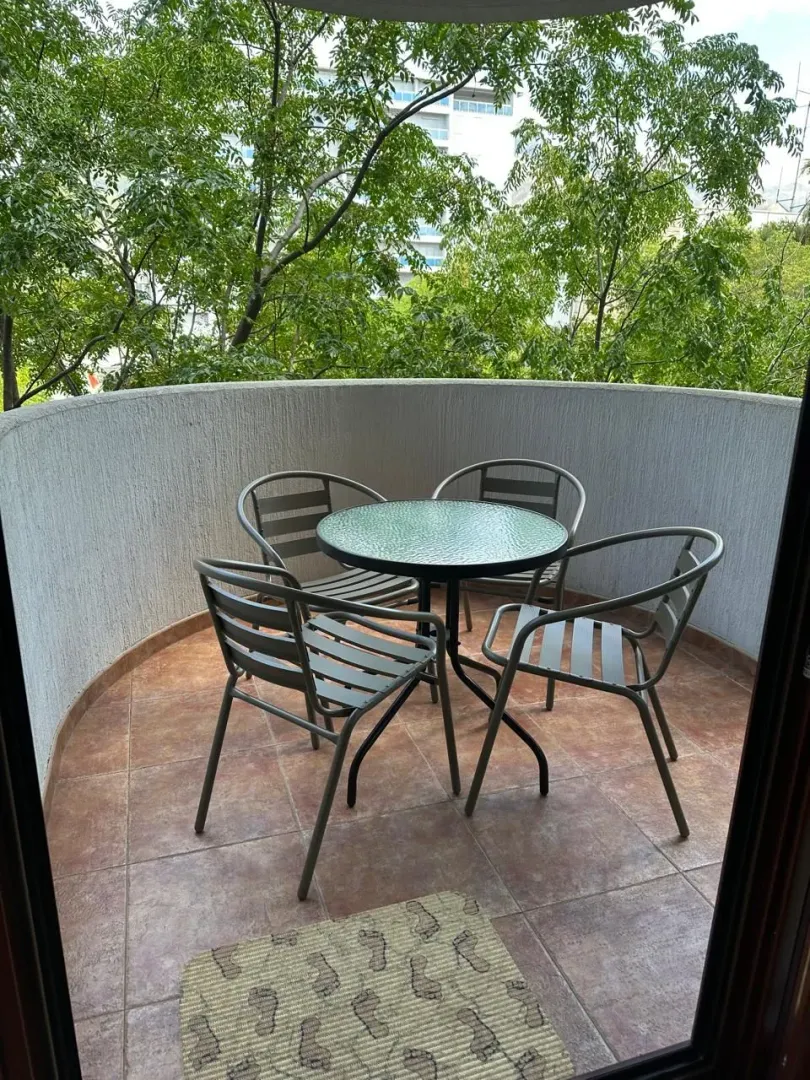 Small furnished balcony with a table and four chairs.