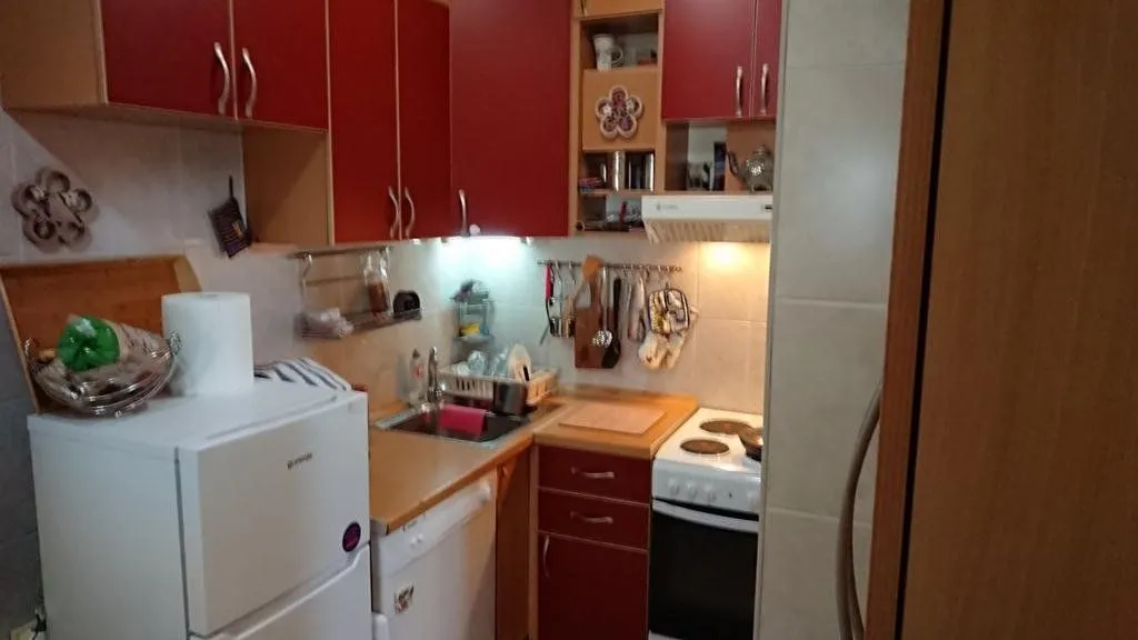 Smaller kitchen with red cabinets and white home appliances.