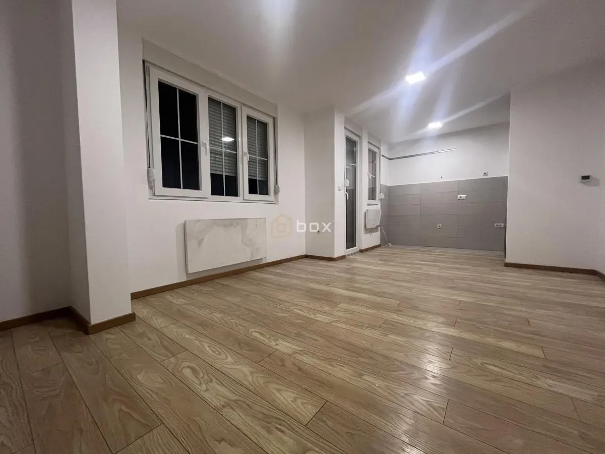 Empty kitchen with grey tiles and parquet flooring.
