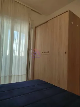 Spavaća soba sa velikim drvenim ormarom i krevetom pored prozora sa zavesama. - image 4