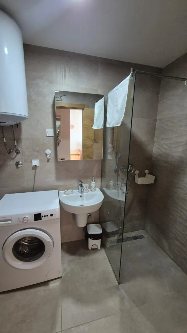 Bathroom equipped with a washbasin, walk-in shower, and washing machine.