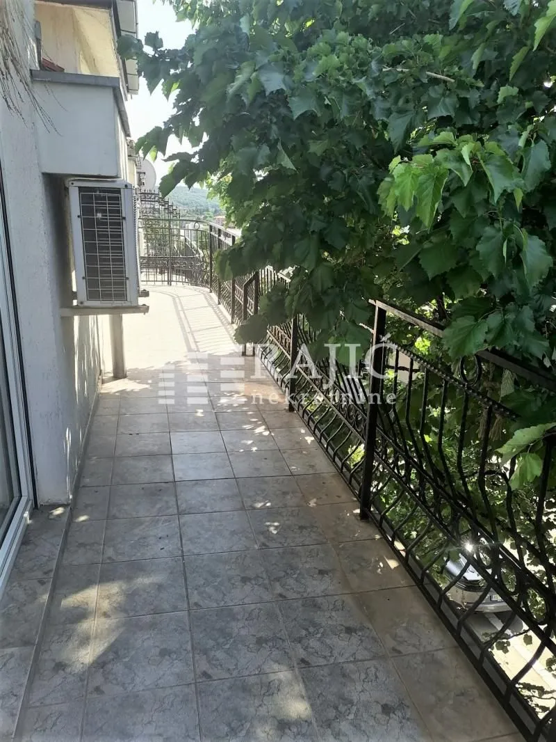 Long tiled balcony with metal railing and green views.