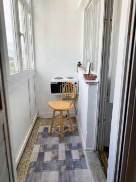 Enclosed balcony with a chair and a small kitchenette unit. - image 9