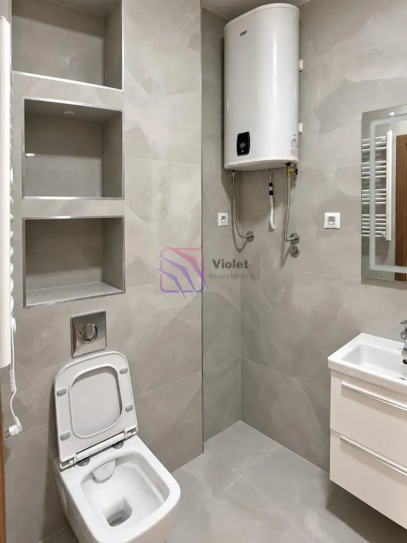 Moderne kupatilo sa siva pločicama, ugradnim WC šoljom, umivaonikom i bojlerom.