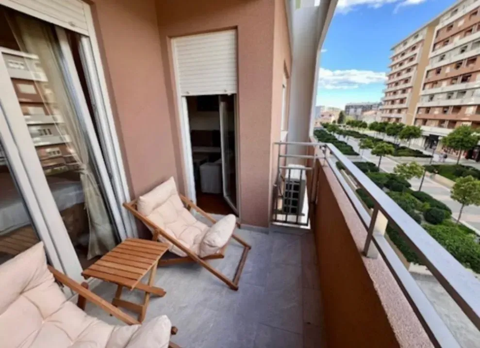 Namtješten balkon sa garniturom za sjedenje i pogledom na grad.