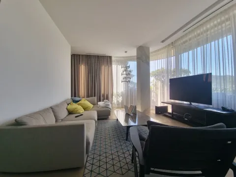 Living room with a sofa, TV, and large windows with an exterior view. - image 17