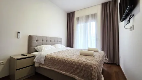 Uredna spavaća soba sa bračnim krevetom, noćnim stočićem i TV-om na zidu. - image 6