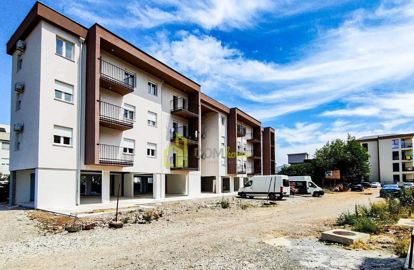 Pogled na spoljašnjost stambene zgrade i parking prostor.