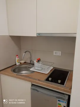Compact kitchen with a sink, built-in cooktop, and a small refrigerator. - image 2