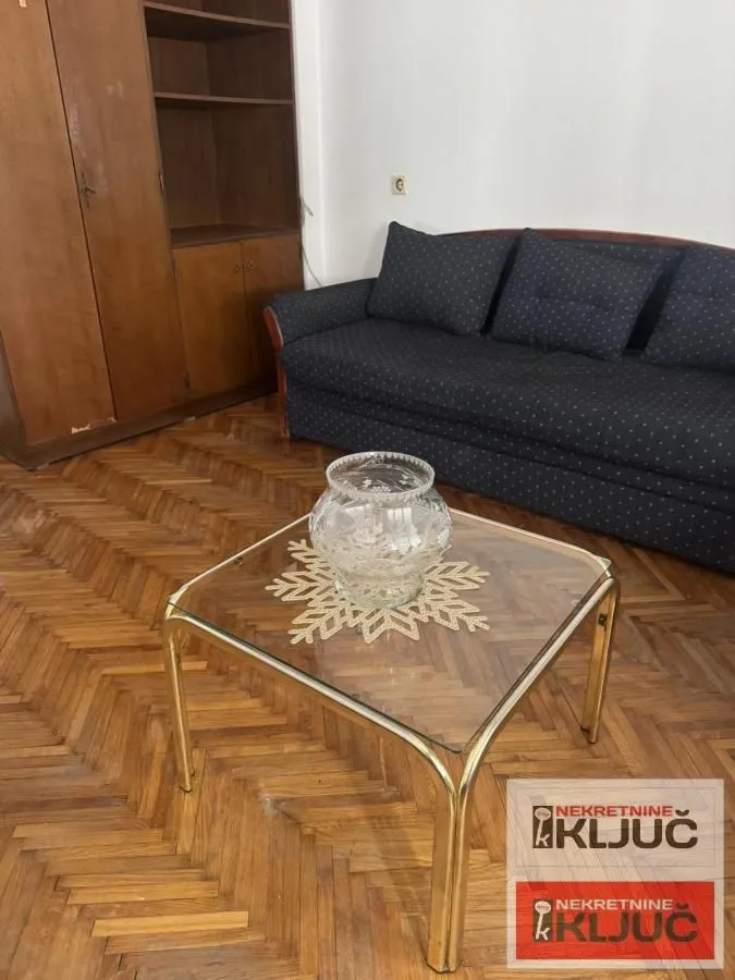 Dnevna soba sa kaučem, drvenim ormanom i stočićem.